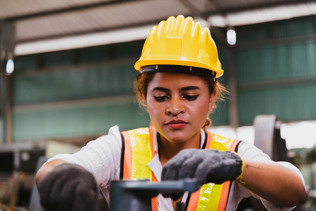 Primer plano de una trabajadora con casco en un entorno industrial, subrayando la relevancia de un ambiente laboral climatizado y seguro.