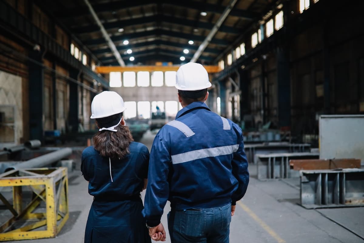 Dos ingenieros con cascos observando un almacén, representando la planificación y ejecución de soluciones de aire acondicionado industrial.
