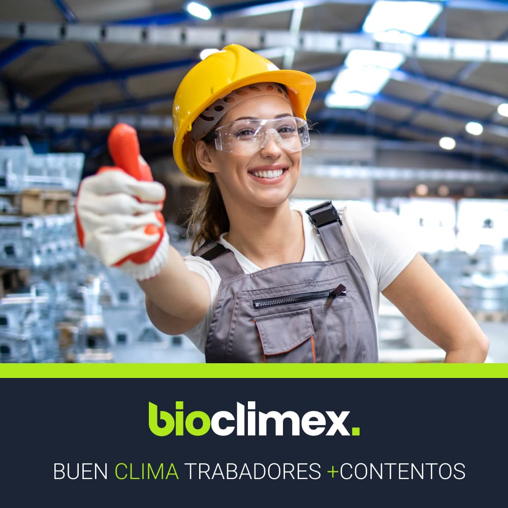Trabajadora de la industria sonriendo mientras opera maquinaria, con los sistemas de aire acondicionado de Bioclimex visibles en el entorno, mejorando la calidad del aire.