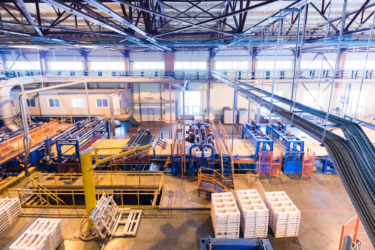 Vista general de una fábrica con trabajadores y maquinaria operativa, subrayando la importancia de la ventilación industrial para mantener un ambiente laboral seguro.