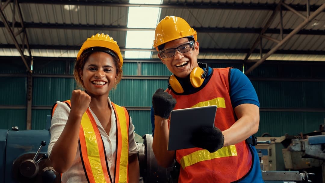 Dos trabajadores de la construcción sonrientes con cascos de seguridad en un sitio industrial, resaltando la colaboración en la implementación de soluciones Bioclimex.