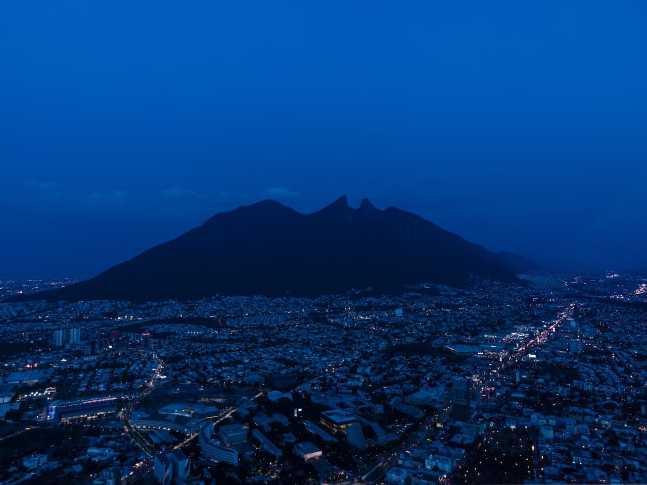 Vista nocturna de la Sierra Madre en Monterrey, capturando la esencia de la ciudad y su entorno natural, representando el aire fresco, alineado con los servicios de Bioclimex.