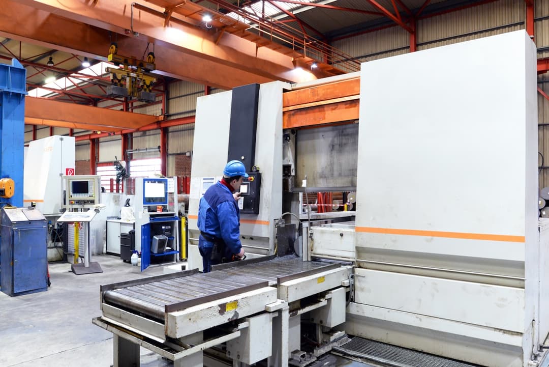 Operario trabajando en una zona de manufactura industrial con maquinaria pesada, resaltando la necesidad de sistemas de ventilación industrial, como los equipos portátiles de Bioclimex.